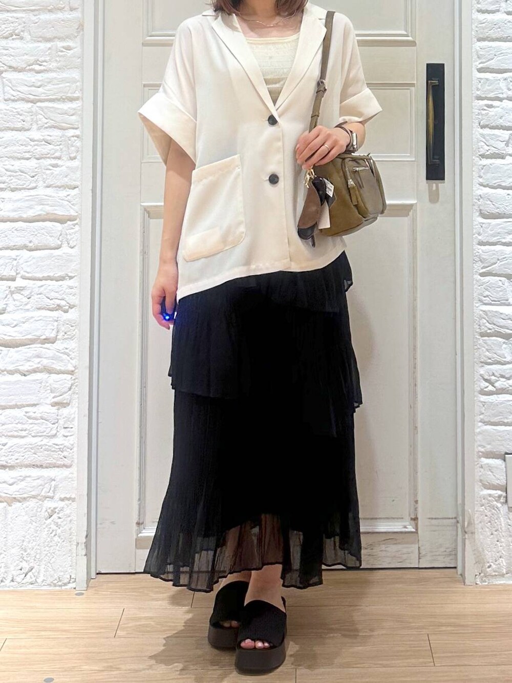 ブラック系のサンダル、ゴールド系のタンクトップ、ブラック系のスカートを着用したレディースの夏コーディネートの3枚目の写真