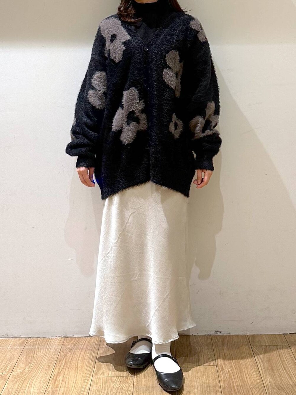 ブラック系のパンプス、ブラック系のニット/セーター、ホワイト系のスカートを着用したレディースの冬コーディネートの2枚目の写真