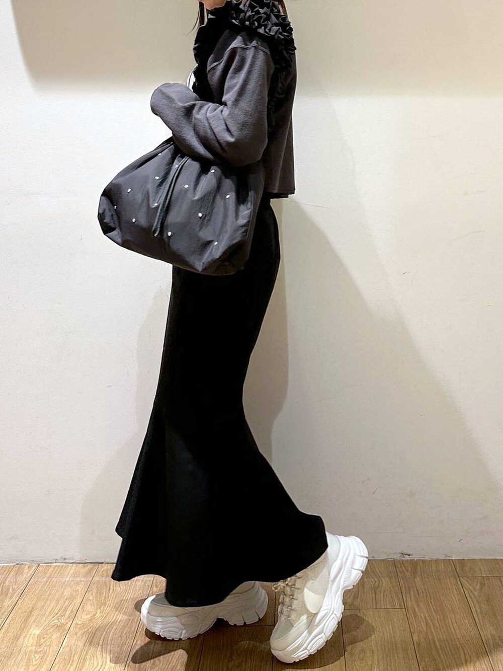 ブラック系のスカート、ブラック系のトートバッグ、ホワイト系のスニーカーを着用したレディースの冬コーディネートの2枚目の写真