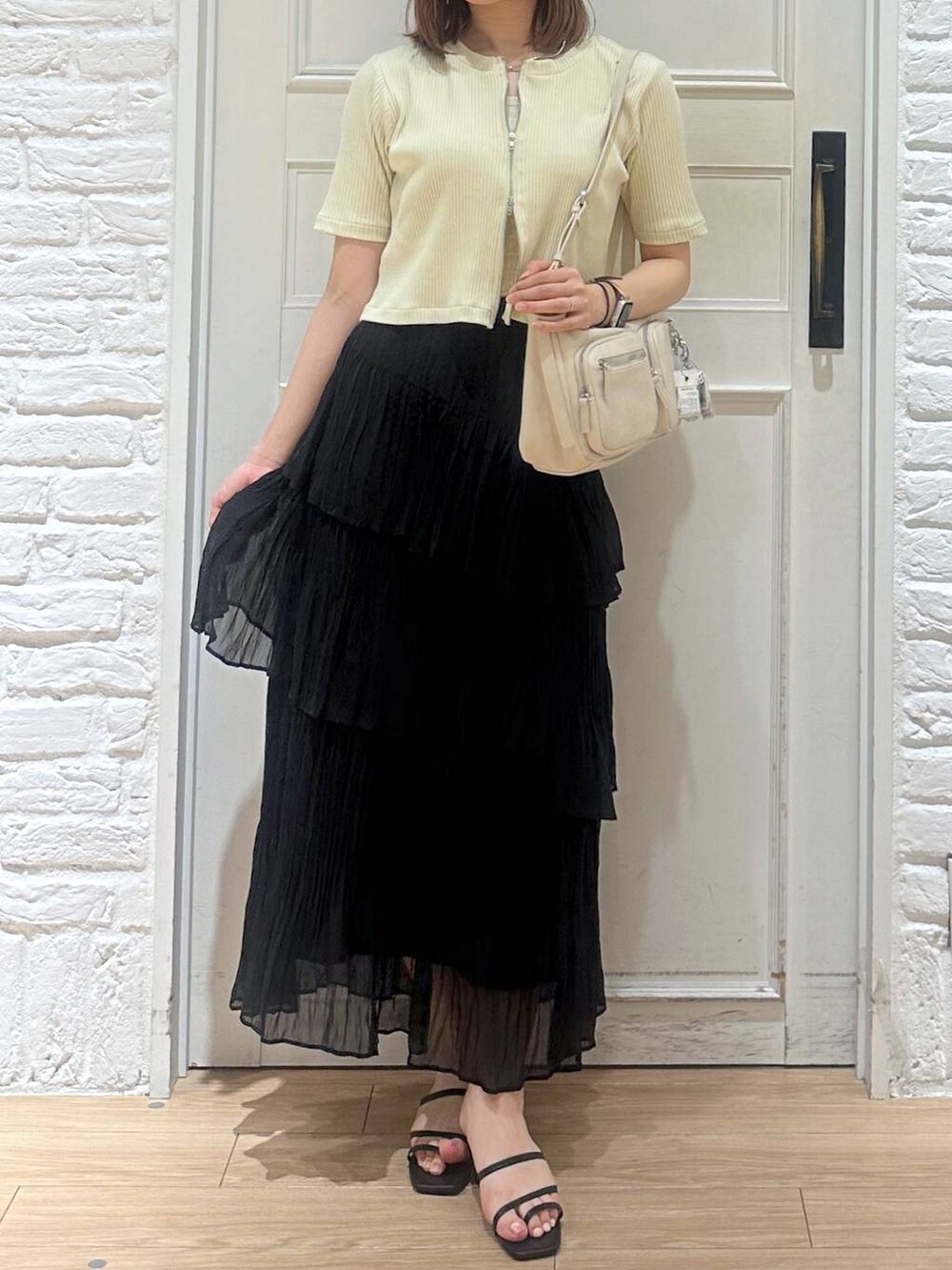 ホワイト系のタンクトップ、ブラック系のサンダル、ブラック系のスカートを着用したレディースの夏コーディネートの2枚目の写真