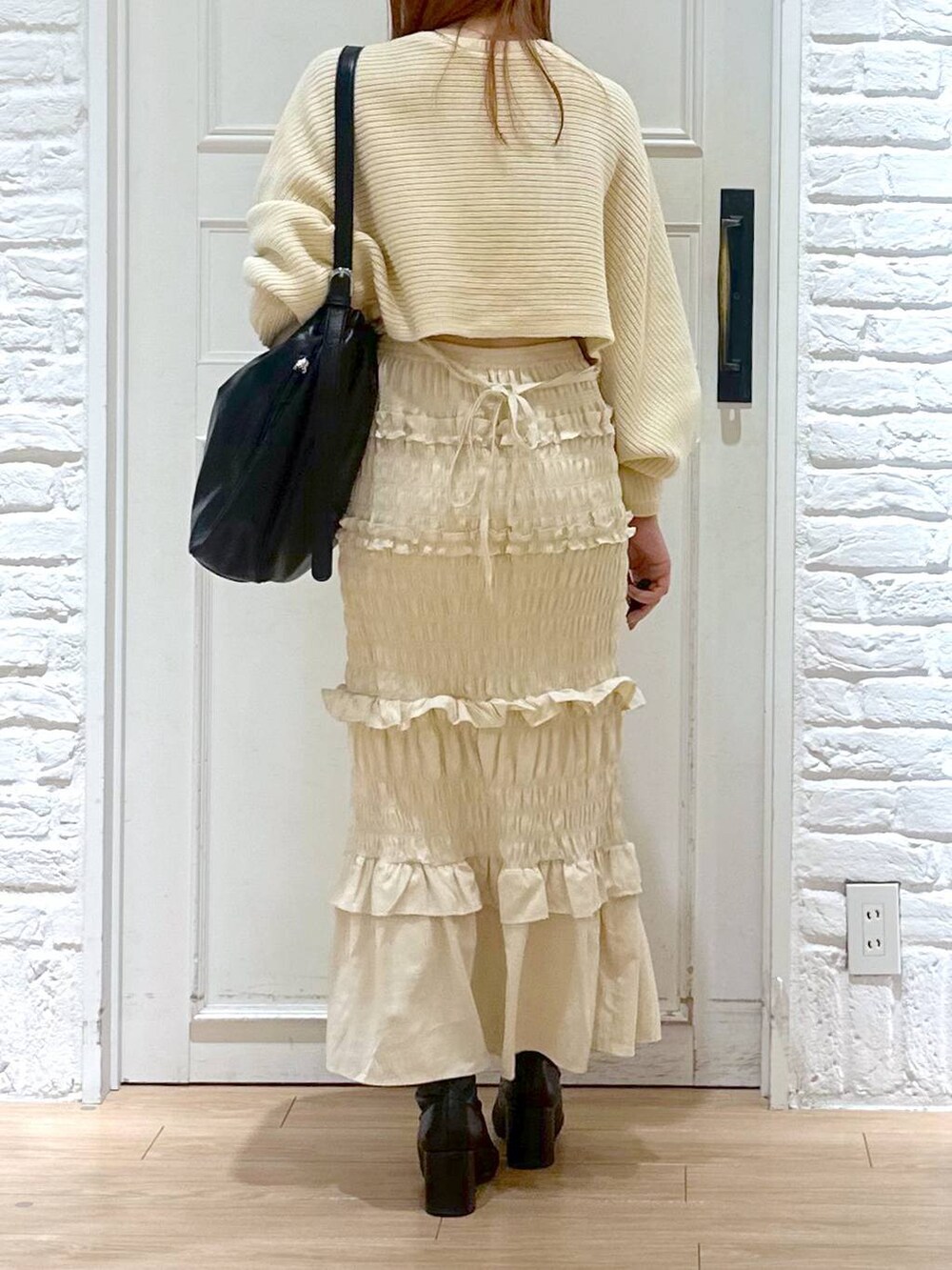 ホワイト系のニット/セーター、ブラック系のブーツ、ブラック系のショルダーバッグを着用したレディースの秋コーディネートの3枚目の写真