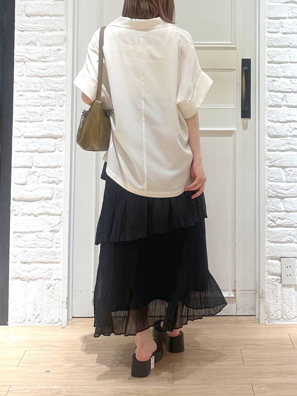 ブラック系のサンダル、ゴールド系のタンクトップ、ブラック系のスカートを着用したレディースの夏コーディネートの4枚目の写真