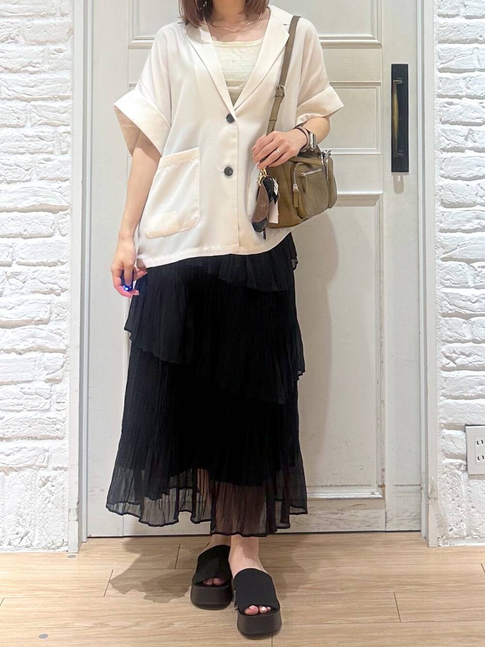 ブラック系のサンダル、ゴールド系のタンクトップ、ブラック系のスカートを着用したレディースの夏コーディネートの2枚目の写真