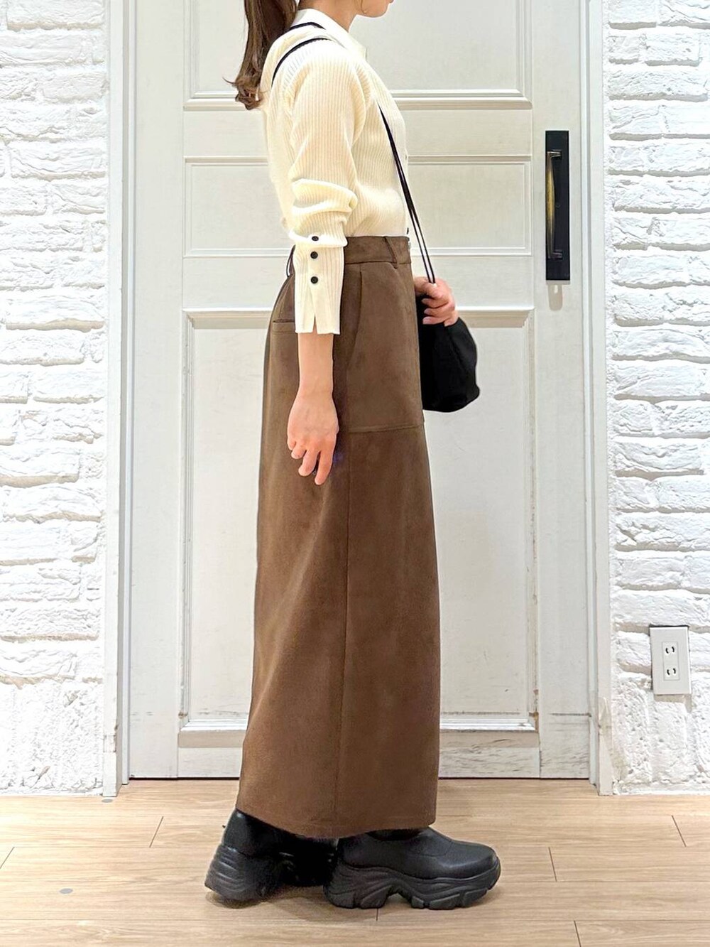 ブラック系のブーツ、ブラウン系のスカート、ブラック系のショルダーバッグを着用したレディースの春コーディネートの4枚目の写真