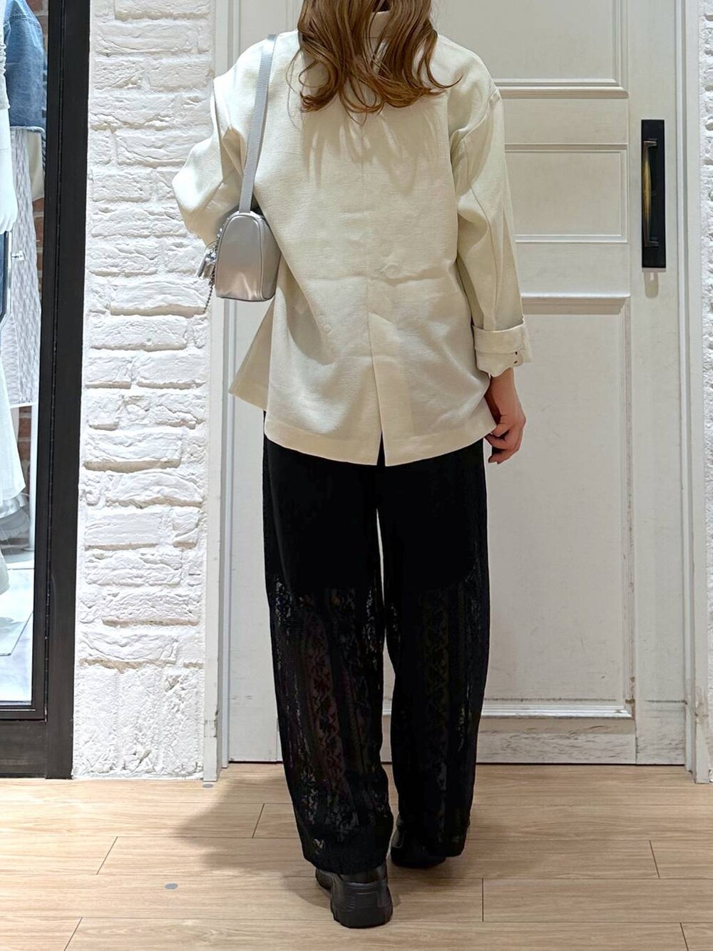 ブラック系のスニーカー、ホワイト系のテーラードジャケット、ホワイト系のTシャツ/カットソーを着用したレディースの春コーディネートの3枚目の写真