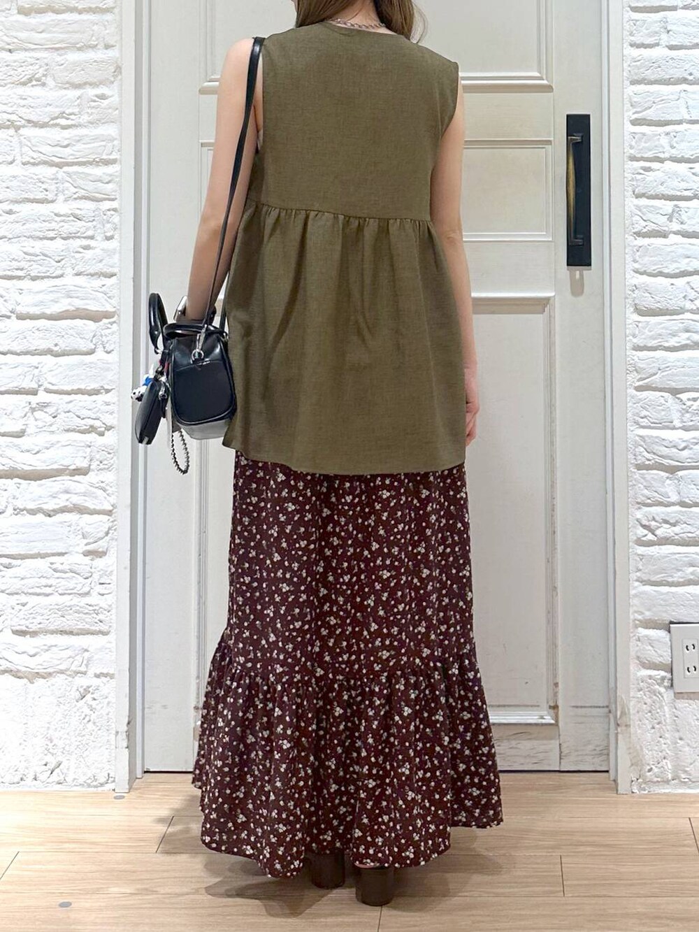 ブラウン系のベスト、ブラウン系のワンピース、ゴールド系のタンクトップを着用したレディースの夏コーディネートの3枚目の写真