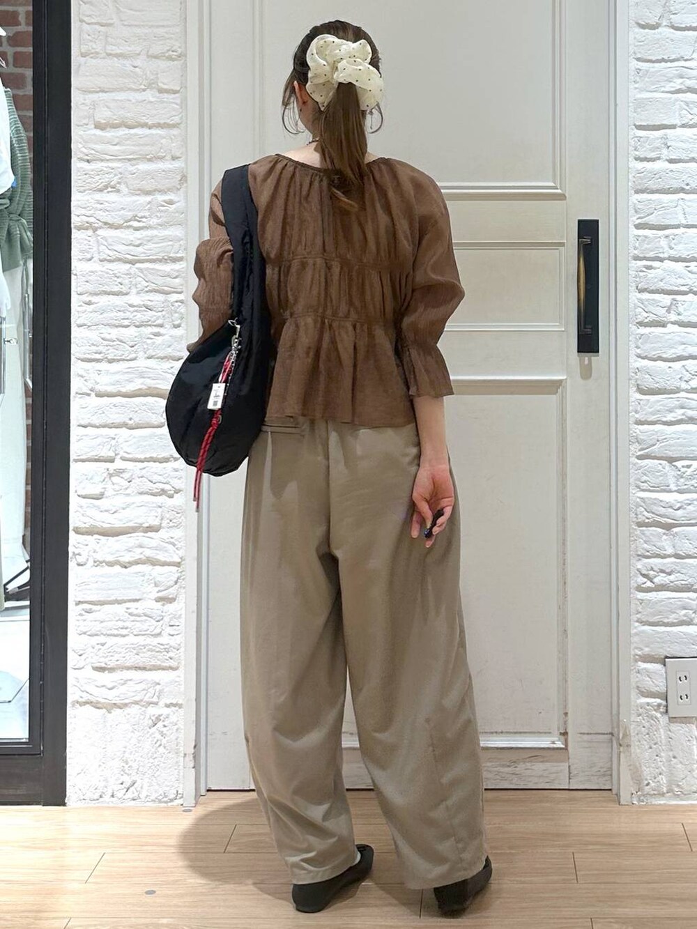 ブラック系のトートバッグ、ブラウン系のシャツ/ブラウス、ベージュ系のその他パンツを着用したレディースの春コーディネートの2枚目の写真