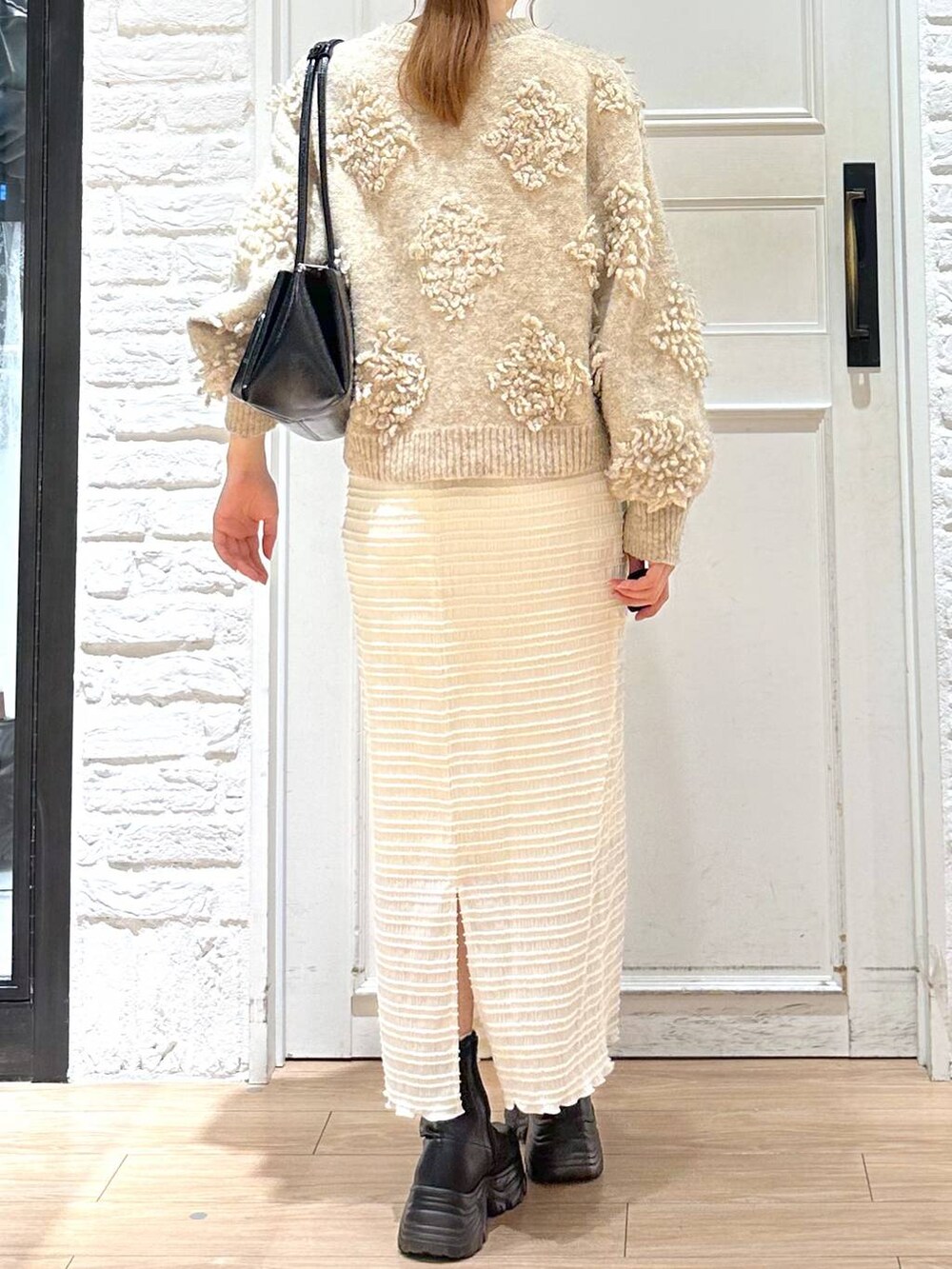 ブラック系のブーツ、ブラック系のショルダーバッグ、ベージュ系のニット/セーターを着用したレディースの冬コーディネートの3枚目の写真