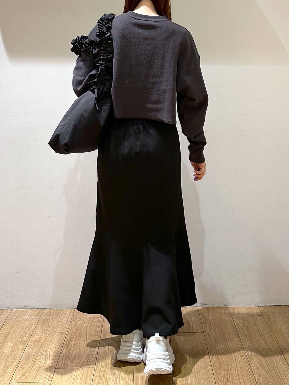 ブラック系のスカート、ブラック系のトートバッグ、ホワイト系のスニーカーを着用したレディースの冬コーディネートの5枚目の写真