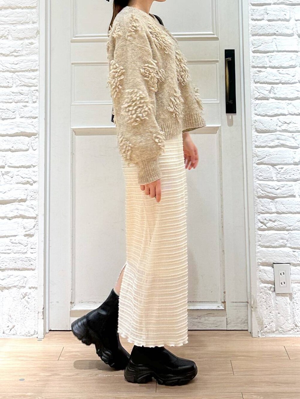 ブラック系のブーツ、ブラック系のショルダーバッグ、ベージュ系のニット/セーターを着用したレディースの冬コーディネートの2枚目の写真