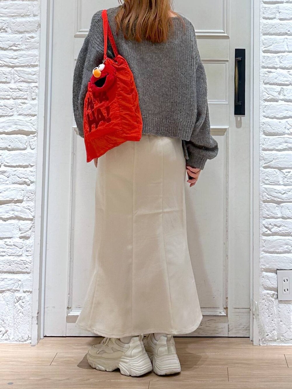 ホワイト系のスカート、ホワイト系のスニーカー、グレー系のニット/セーターを着用したレディースの秋コーディネートの3枚目の写真