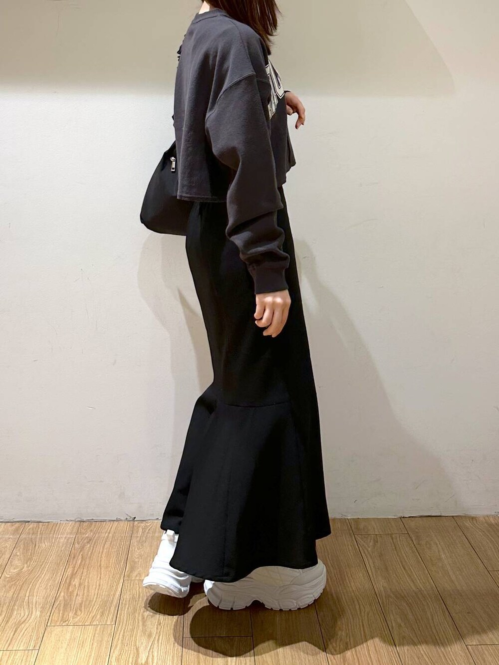 ブラック系のスカート、ブラック系のトートバッグ、ホワイト系のスニーカーを着用したレディースの冬コーディネートの3枚目の写真