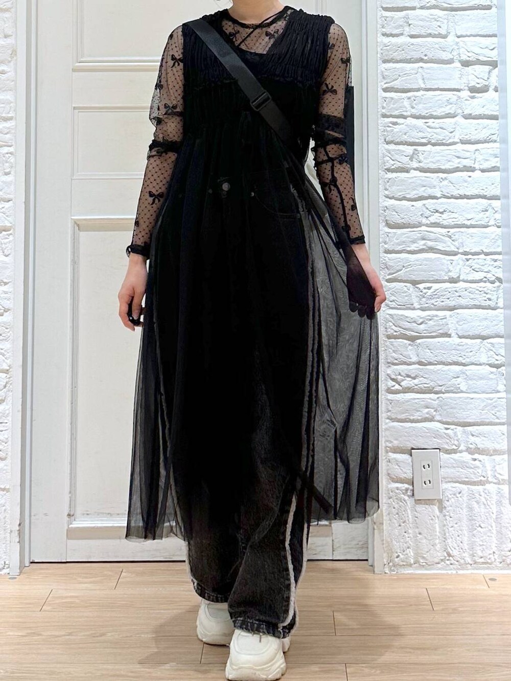 ブラック系のデニムパンツ、ホワイト系のスニーカー、ブラック系のTシャツ/カットソーを着用したレディースの秋コーディネートの2枚目の写真