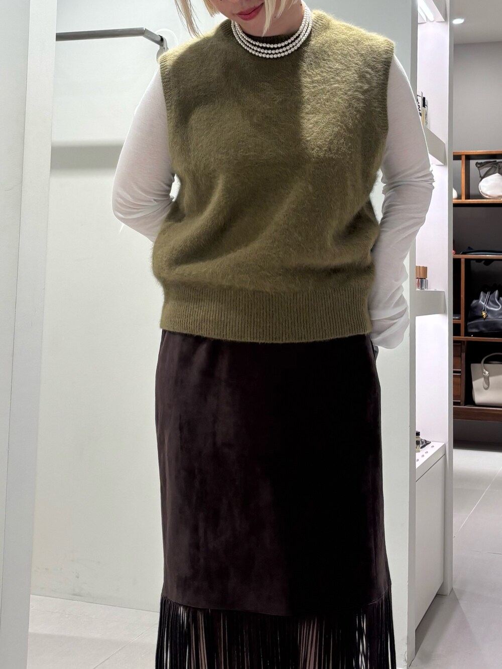 ホワイト系のTシャツ/カットソー、グリーン系のベスト、ブラック系のブーツを着用したレディースの夏コーディネートの3枚目の写真