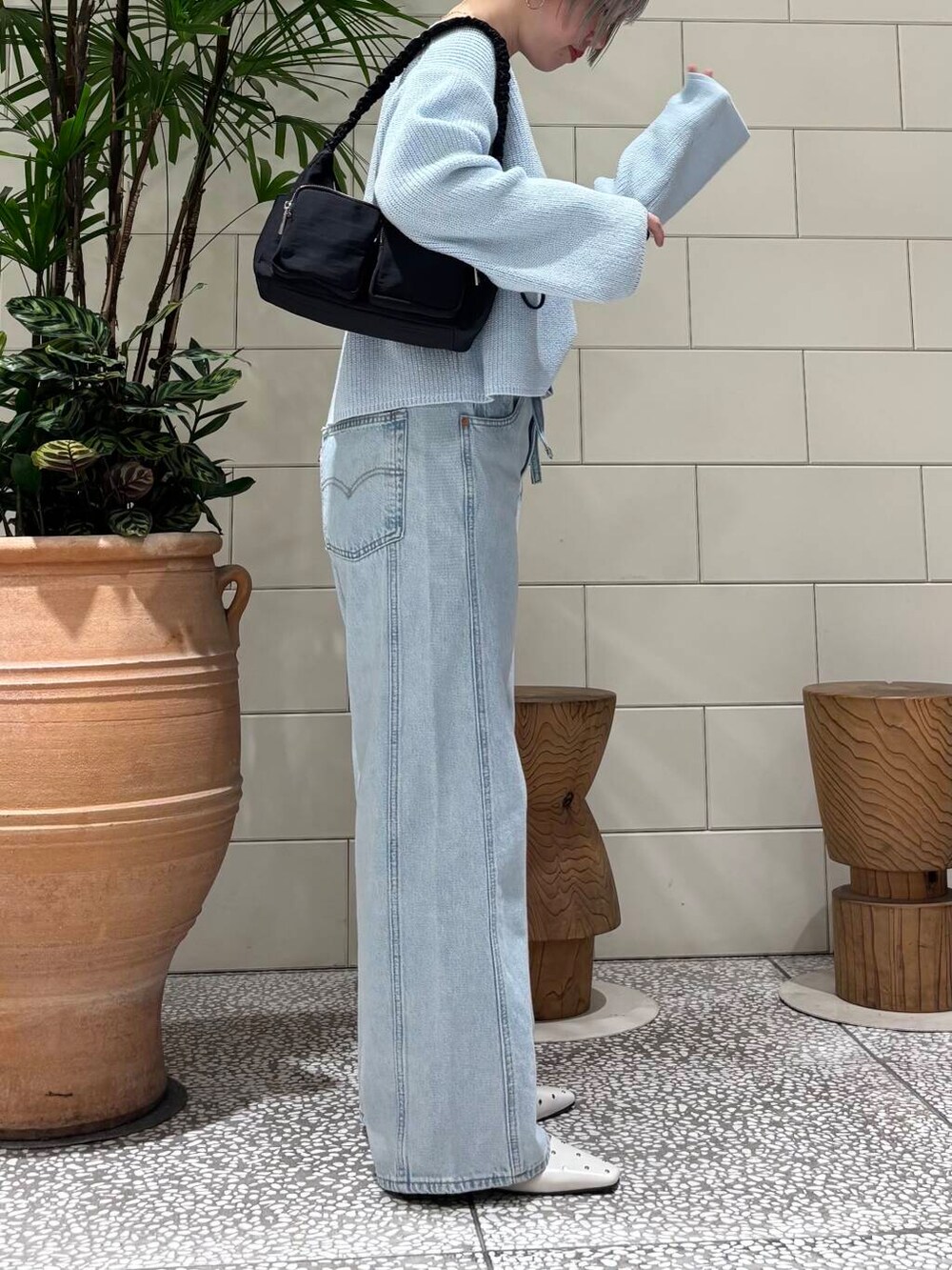 ブラック系のショルダーバッグ、ホワイト系のパンプス、ブルー系のニット/セーターを着用したレディースの春コーディネートの3枚目の写真