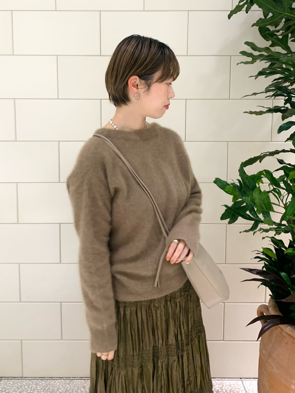 イエロー系のカーディガン/ボレロ、ブラウン系のスカート、ベージュ系のショルダーバッグを着用したレディースの冬コーディネートの3枚目の写真