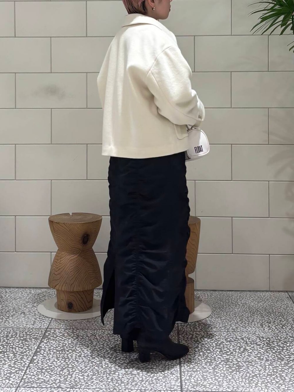 ブラック系のブーツ、ホワイト系のボストンバッグ、ブラック系のスカートを着用したレディースの冬コーディネートの3枚目の写真