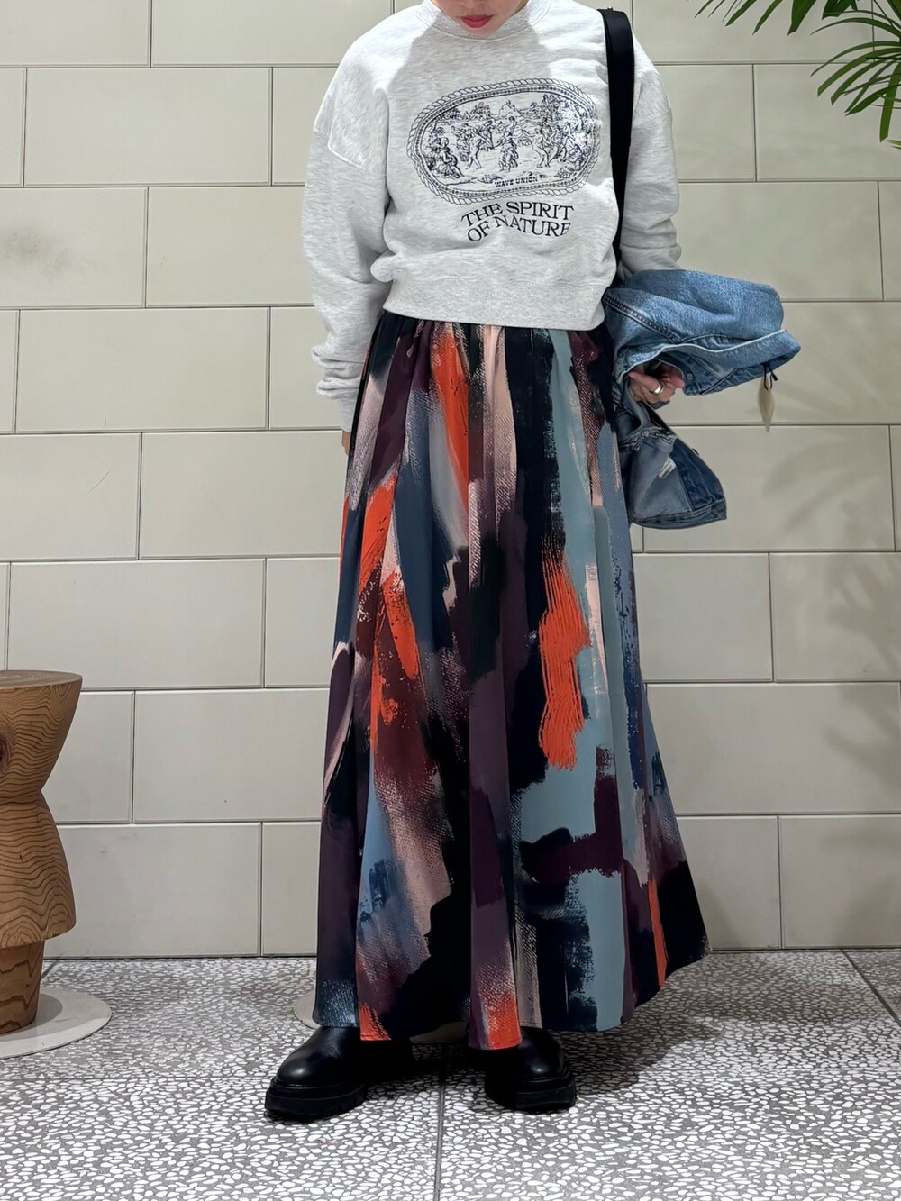 グレー系のスウェット、ピンク系のスカート、ブルー系のデニムジャケットを着用したレディースの冬コーディネートの2枚目の写真