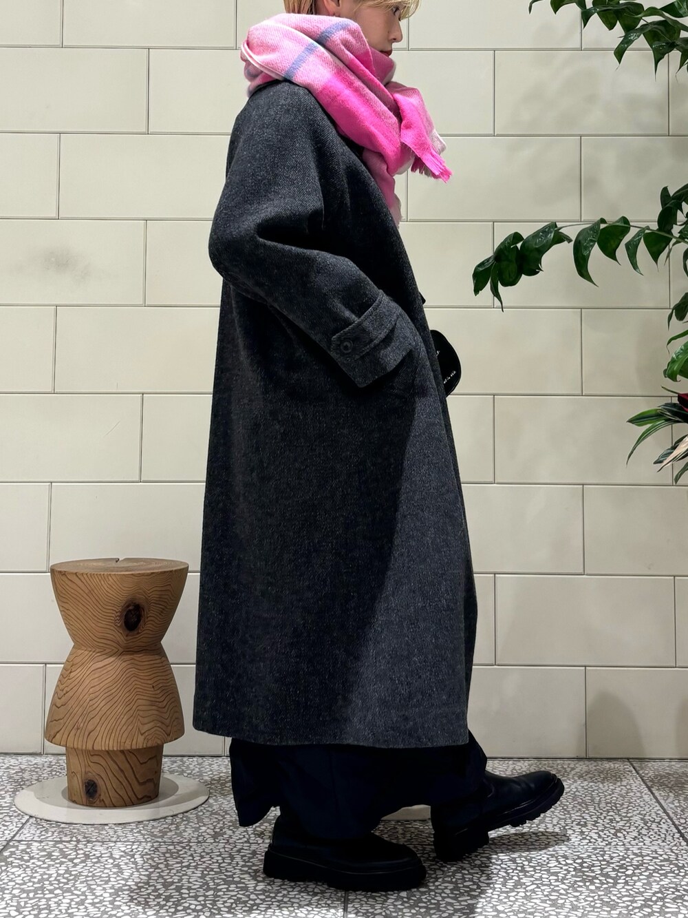 ブラック系のステンカラーコート、ブラック系のスカート、レッド系のTシャツ/カットソーを着用したレディースの秋コーディネートの3枚目の写真