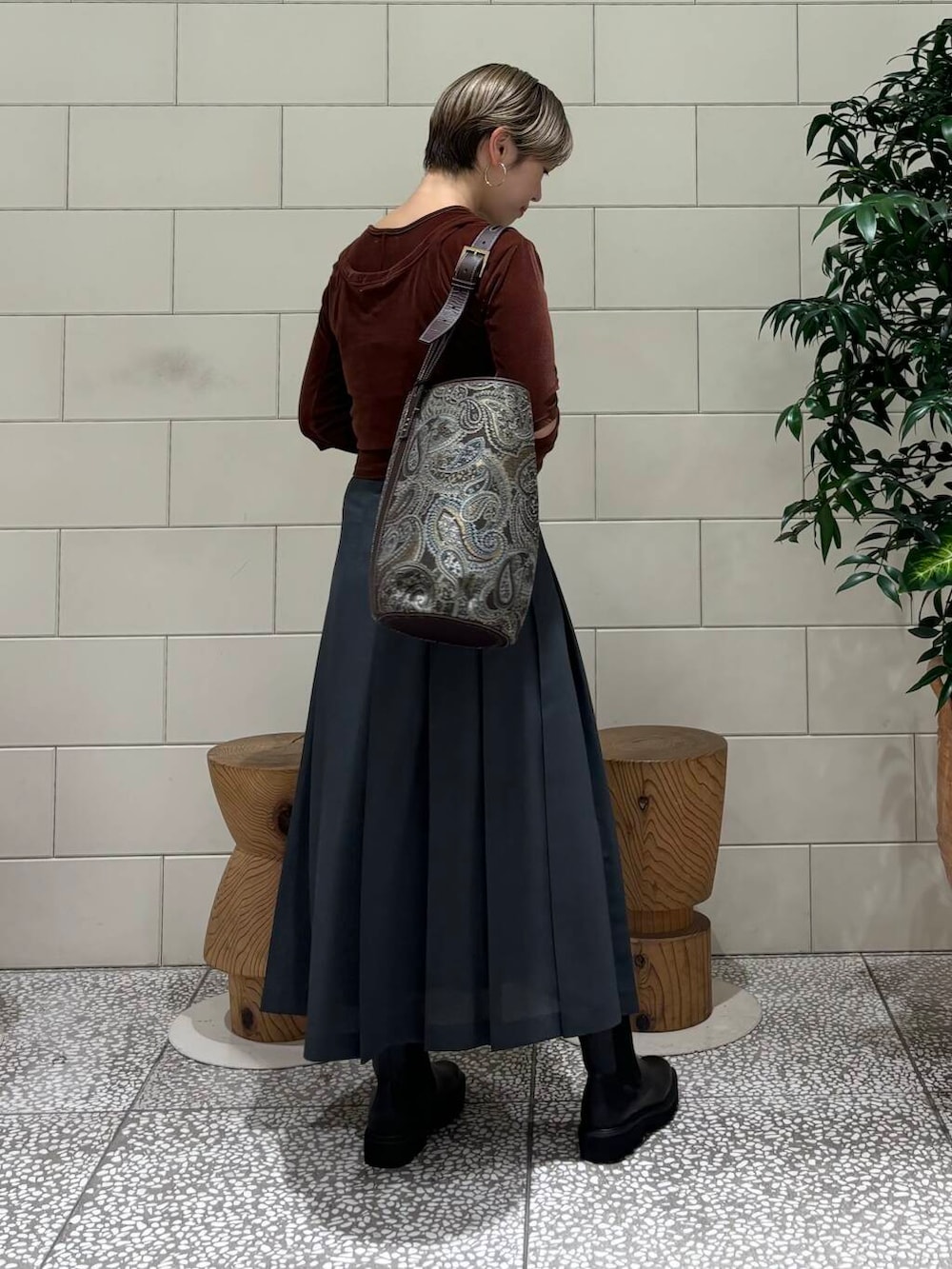 グレー系のスカート、ブラウン系のTシャツ/カットソー、ブラック系のブーツを着用したレディースの秋コーディネートの4枚目の写真