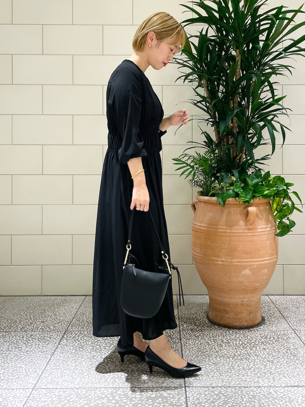 ブラック系のショルダーバッグ、ブラック系のワンピース、ブラック系のパンプスを着用したレディースの春コーディネートの2枚目の写真
