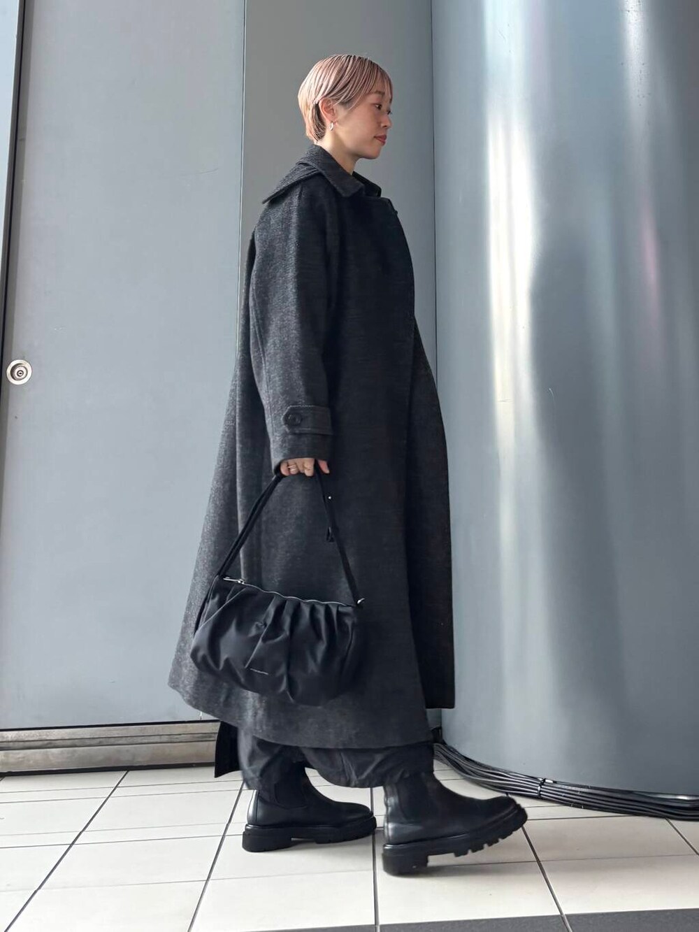 ブラック系のステンカラーコート、ブラック系のスカート、ブラック系のニット/セーターを着用したレディースの冬コーディネートの2枚目の写真