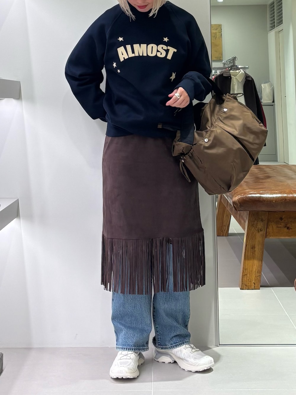 ブラウン系のスカート、ブルー系のデニムパンツ、ブラウン系のショルダーバッグを着用したレディースの秋コーディネートの4枚目の写真