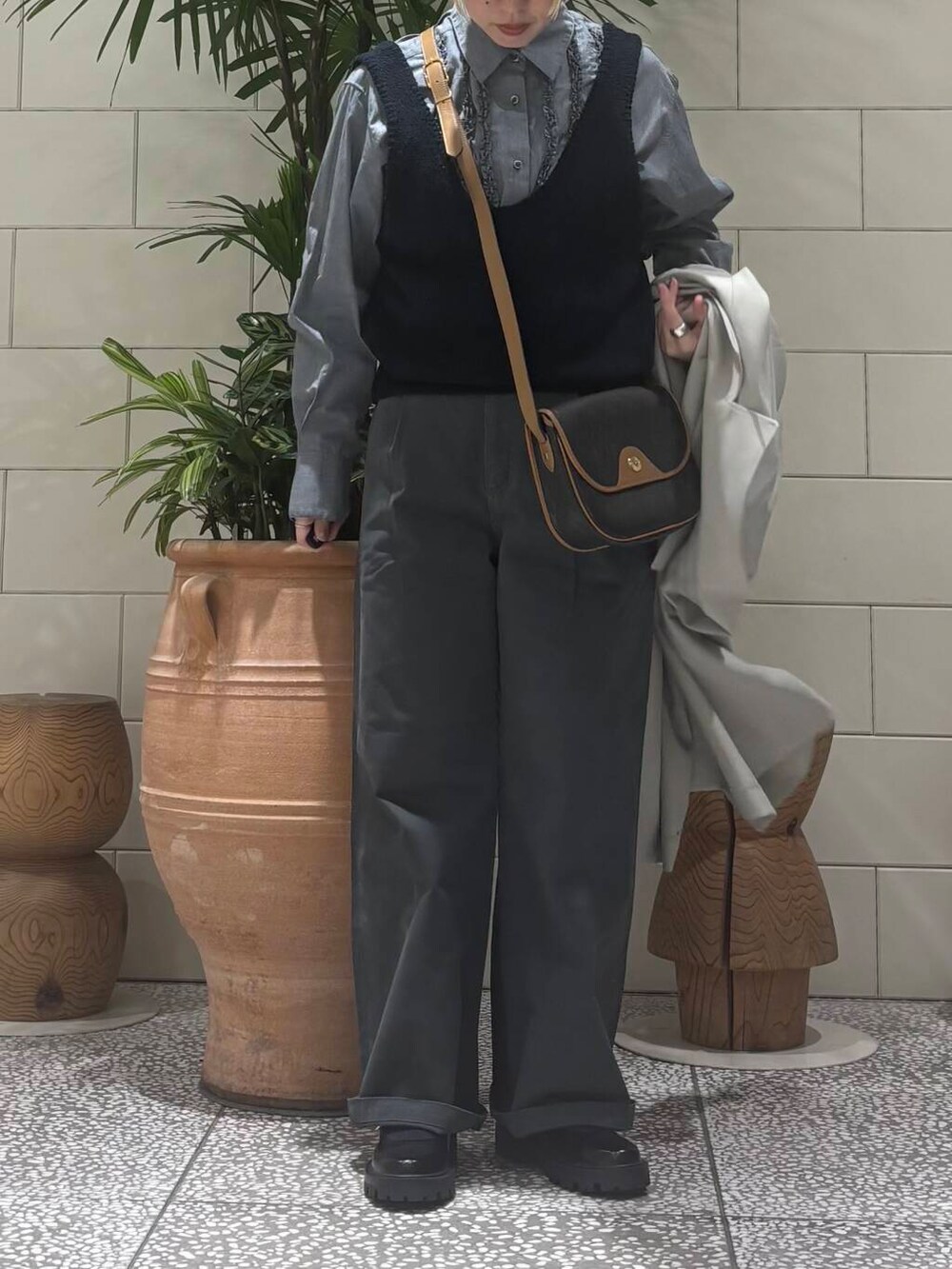 グレー系のその他パンツ、グリーン系のトレンチコート、ブルー系のベストを着用したレディースの冬コーディネートの3枚目の写真