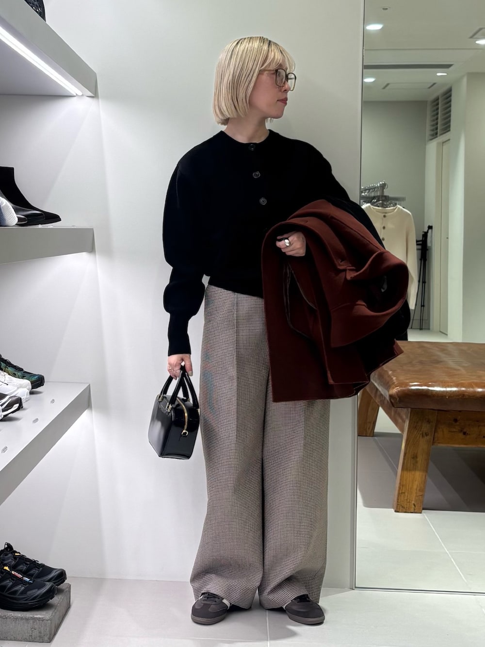 ブラウン系のステンカラーコート、ブラック系のカーディガン/ボレロ、ブラック系のショルダーバッグを着用したレディースの秋コーディネートの3枚目の写真