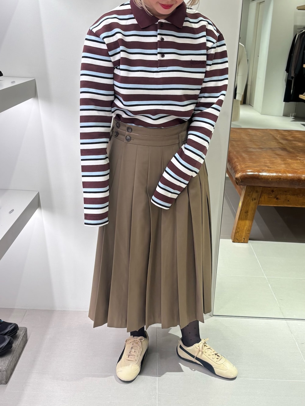 ベージュ系のスニーカー、グリーン系のスカート、その他のポロシャツを着用したレディースの秋コーディネートの2枚目の写真