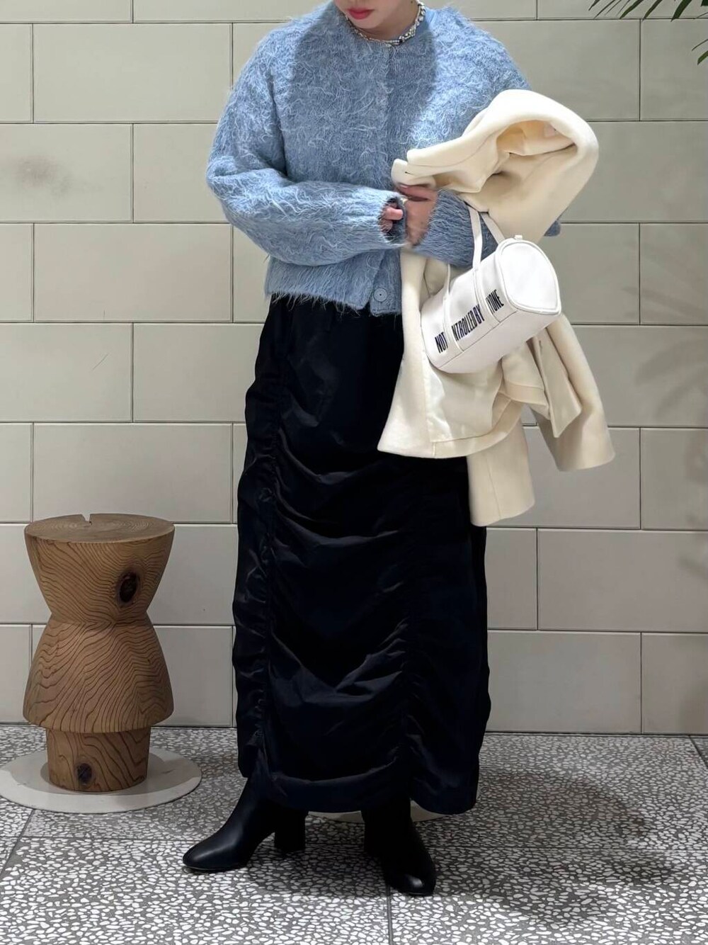 ブラック系のブーツ、ホワイト系のボストンバッグ、ブラック系のスカートを着用したレディースの冬コーディネートの2枚目の写真