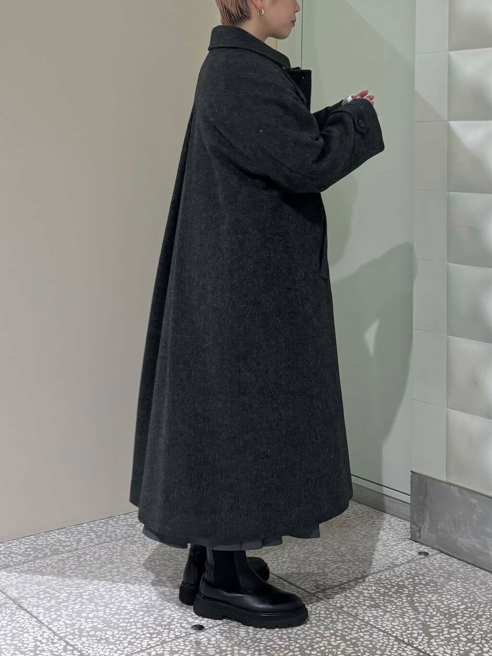 ブラック系のステンカラーコート、グレー系のスカート、グレー系のカーディガン/ボレロを着用したレディースの冬コーディネートの3枚目の写真