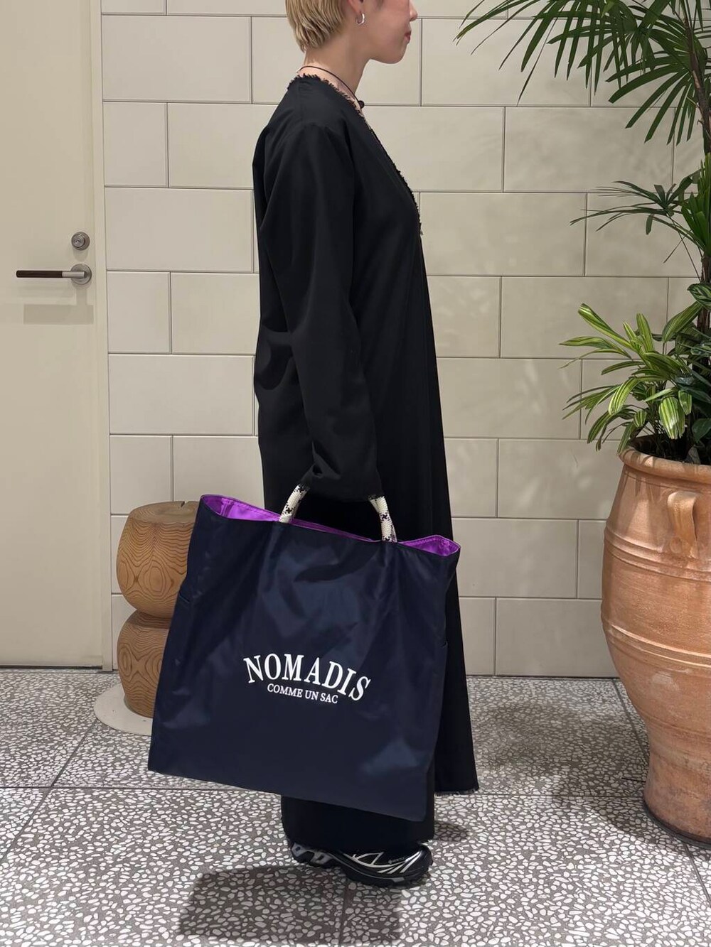 ブラック系のワンピース、ブルー系のトートバッグ、ブラウン系のネックレスを着用したレディースの冬コーディネートの2枚目の写真