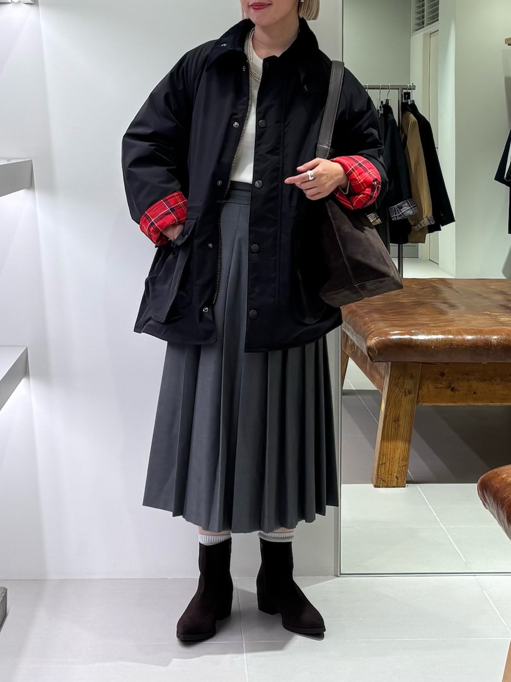 グリーン系のスカート、ブラウン系のトートバッグ、ブラック系のその他アウターを着用したレディースの秋コーディネートの2枚目の写真