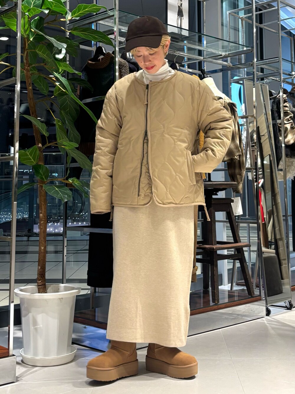 ホワイト系のTシャツ/カットソー、ベージュ系のダウンジャケット/コート、ブラウン系のブーツを着用したレディースの秋コーディネートの2枚目の写真