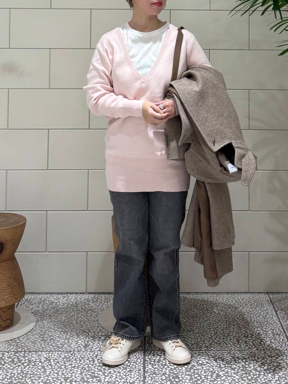 ブラック系のデニムパンツ、ブラウン系のステンカラーコート、ホワイト系のTシャツ/カットソーを着用したレディースの冬コーディネートの3枚目の写真