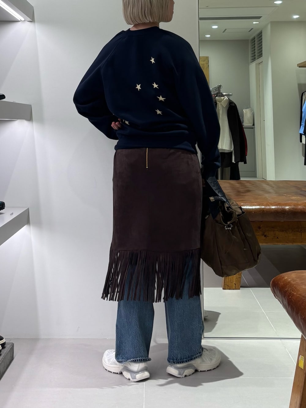 ブラウン系のスカート、ブルー系のデニムパンツ、ブラウン系のショルダーバッグを着用したレディースの秋コーディネートの3枚目の写真