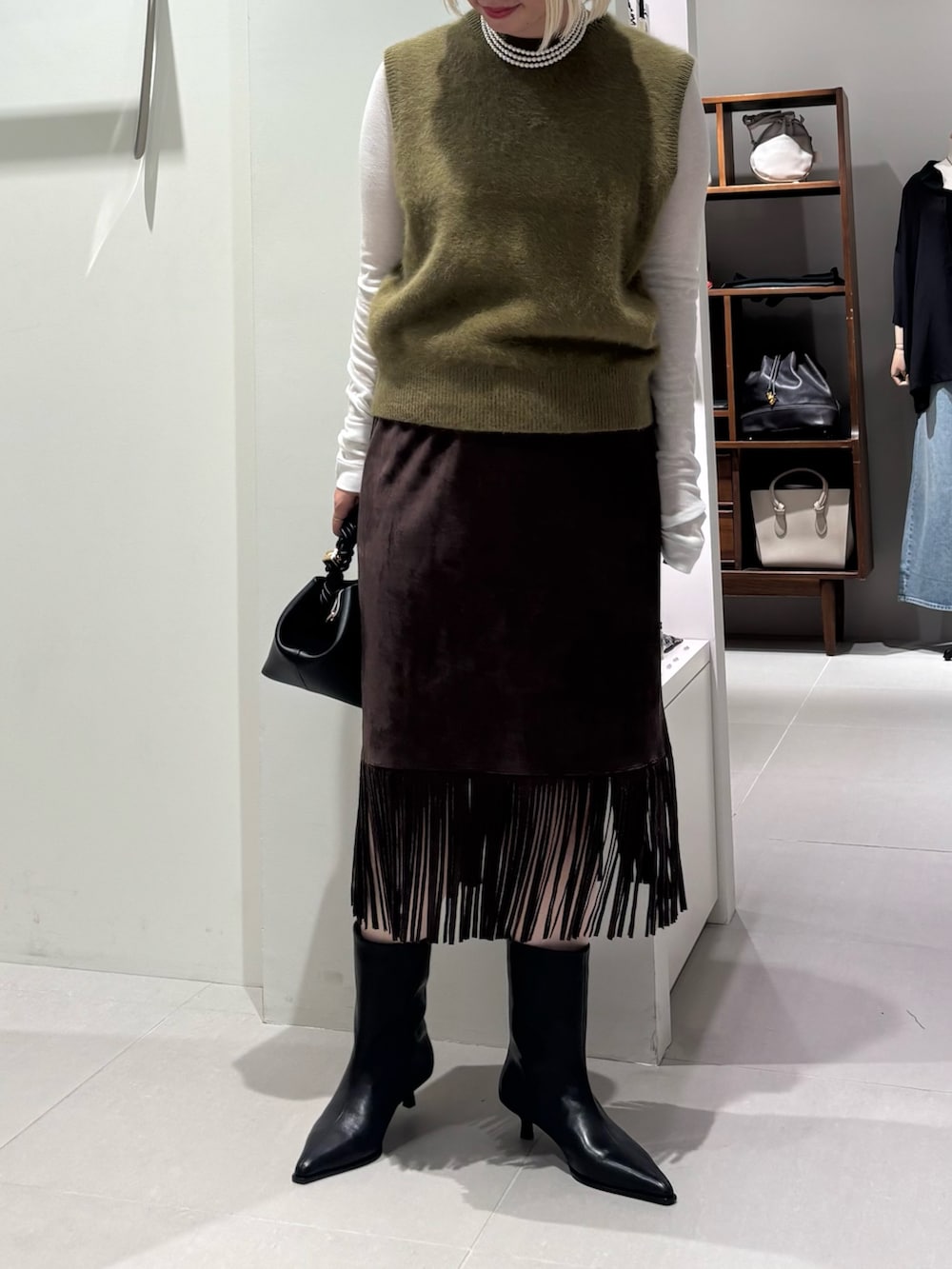 ホワイト系のTシャツ/カットソー、グリーン系のベスト、ブラック系のブーツを着用したレディースの夏コーディネートの2枚目の写真