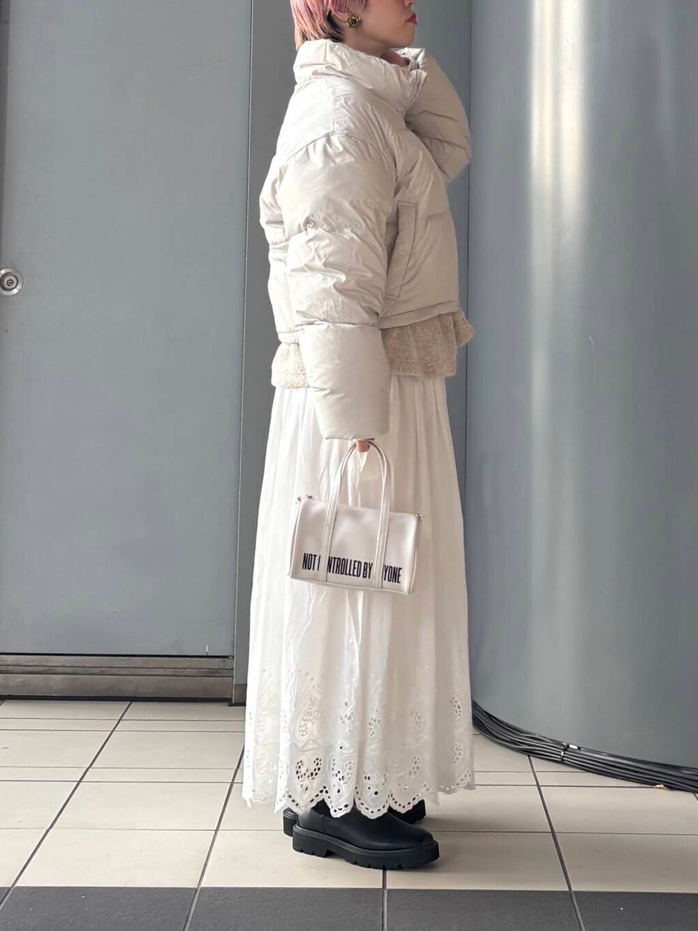 ホワイト系のボストンバッグ、ホワイト系のスカート、ホワイト系のダウンジャケット/コートを着用したレディースの冬コーディネートの3枚目の写真