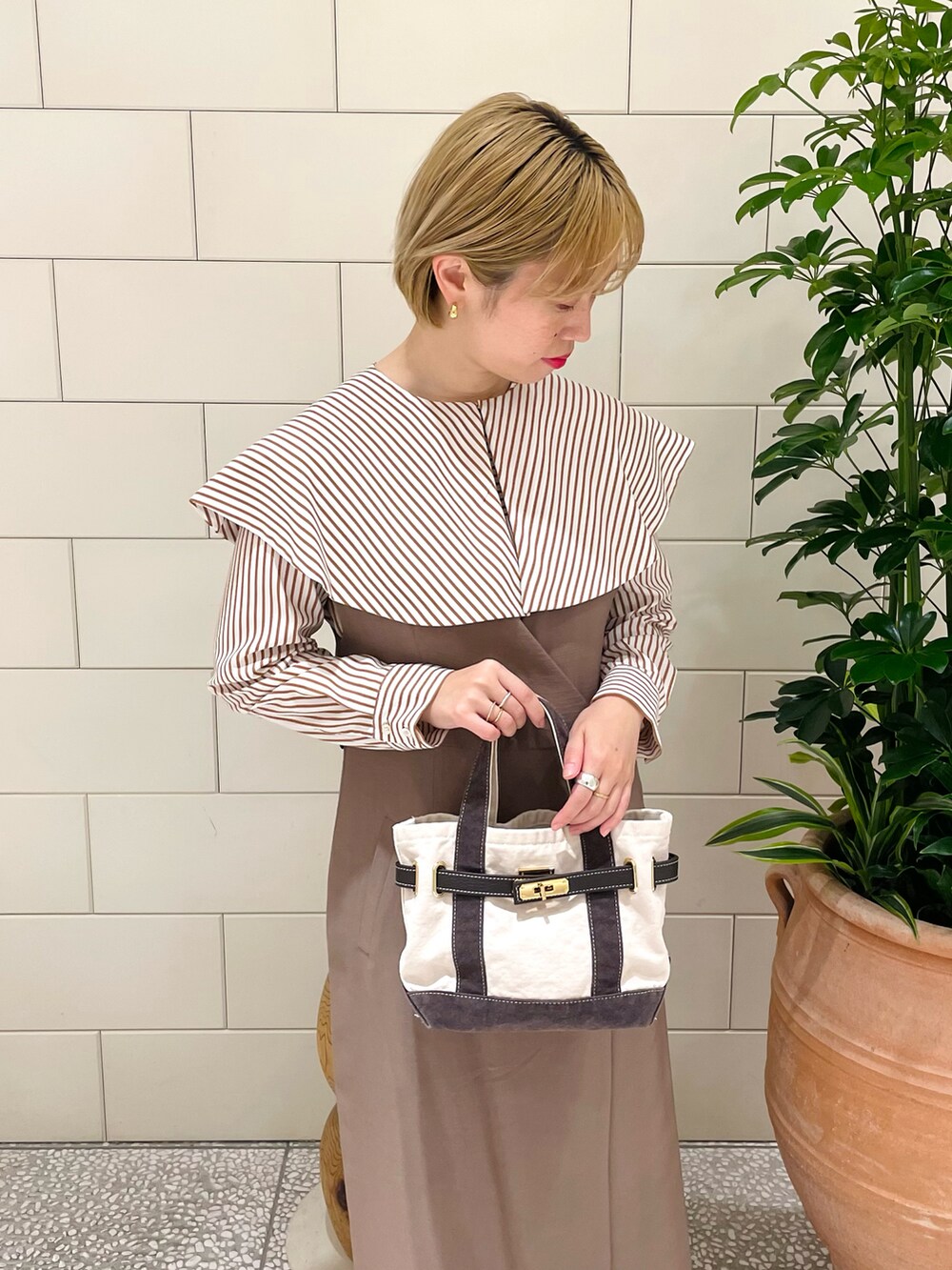 ホワイト系のシャツ/ブラウス、ブラウン系のワンピース、ホワイト系のバッグを着用したレディースの春コーディネートの3枚目の写真