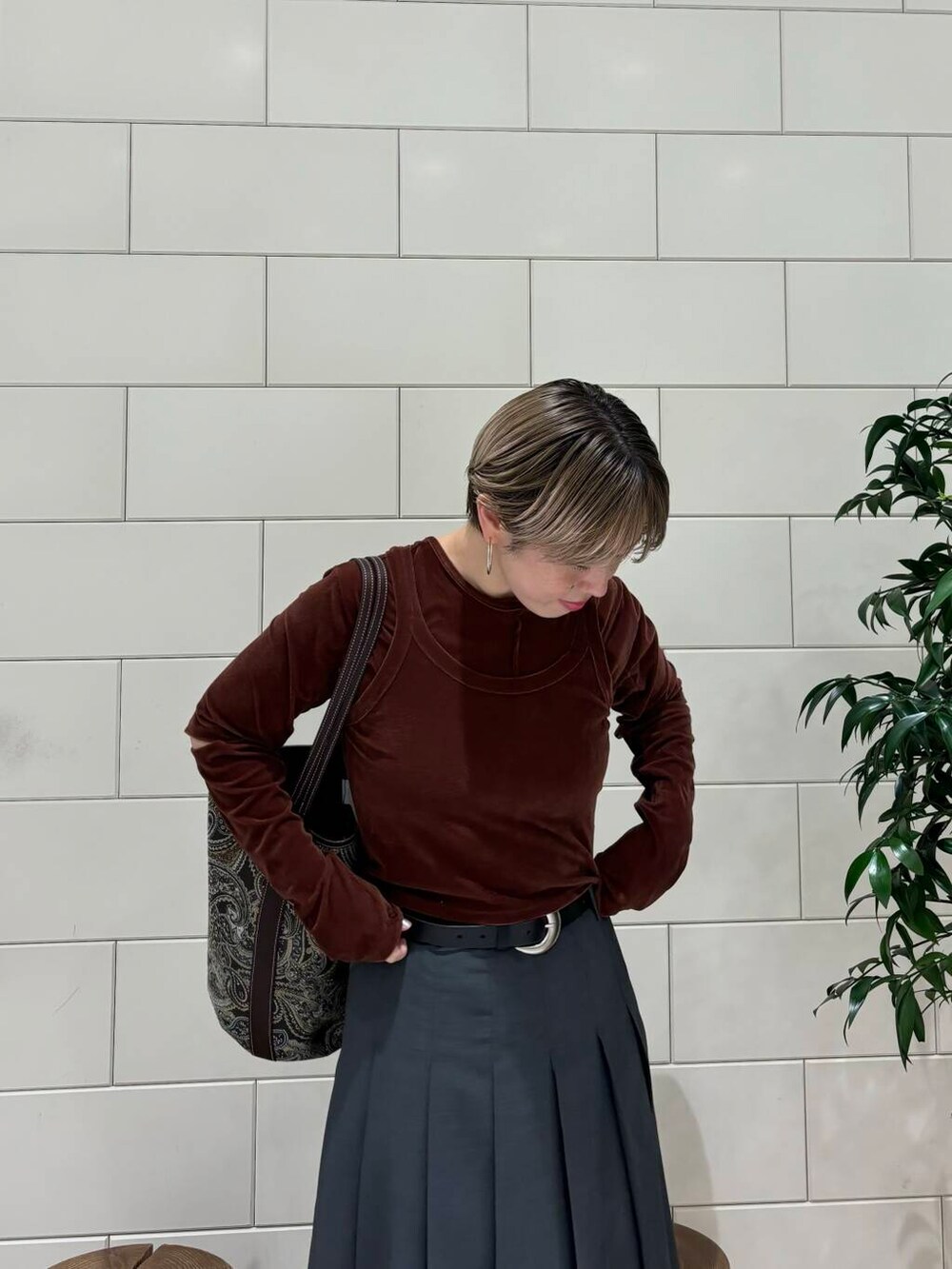 グレー系のスカート、ブラウン系のTシャツ/カットソー、ブラック系のブーツを着用したレディースの秋コーディネートの5枚目の写真