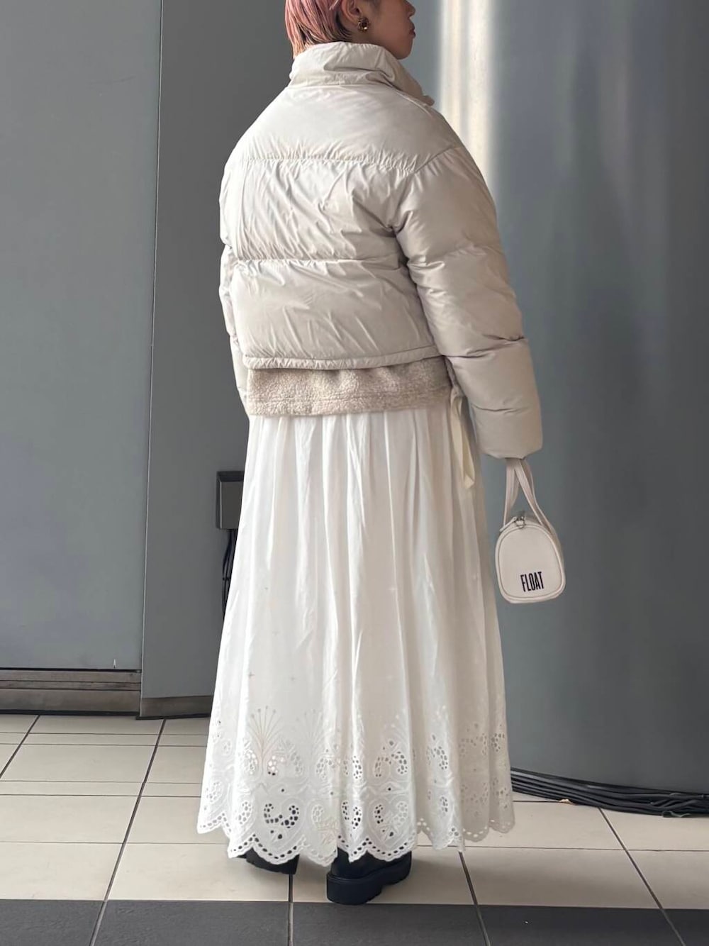 ホワイト系のボストンバッグ、ホワイト系のスカート、ホワイト系のダウンジャケット/コートを着用したレディースの冬コーディネートの4枚目の写真