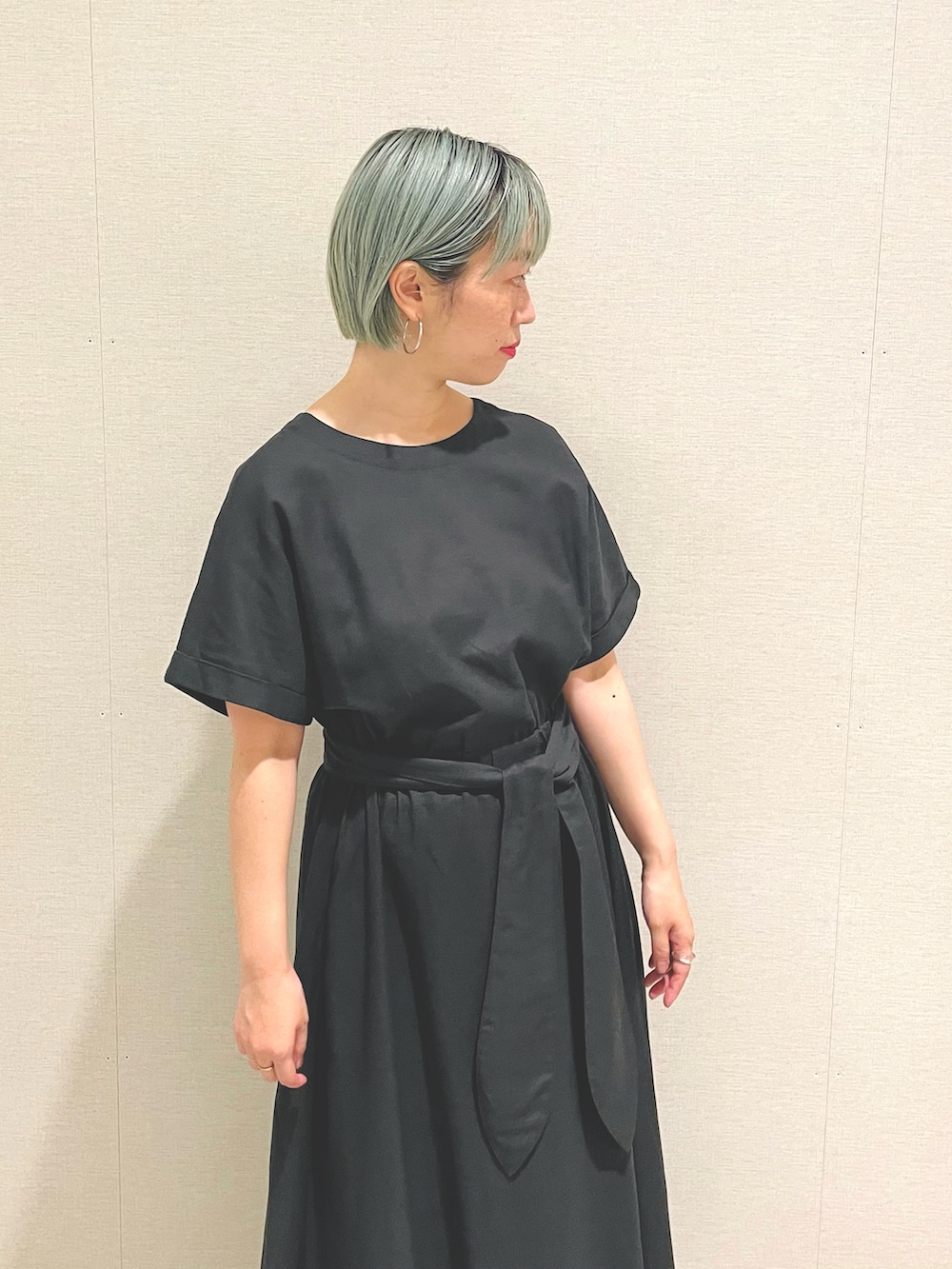 グレー系のワンピース、グリーン系のサンダル、シルバー系のピアス（両耳用）を着用したレディースの夏コーディネートの3枚目の写真