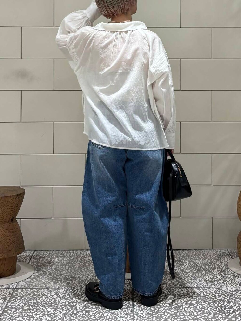 ブルー系のデニムパンツ、ブラック系のショルダーバッグ、ホワイト系のシャツ/ブラウスを着用したレディースの春コーディネートの4枚目の写真