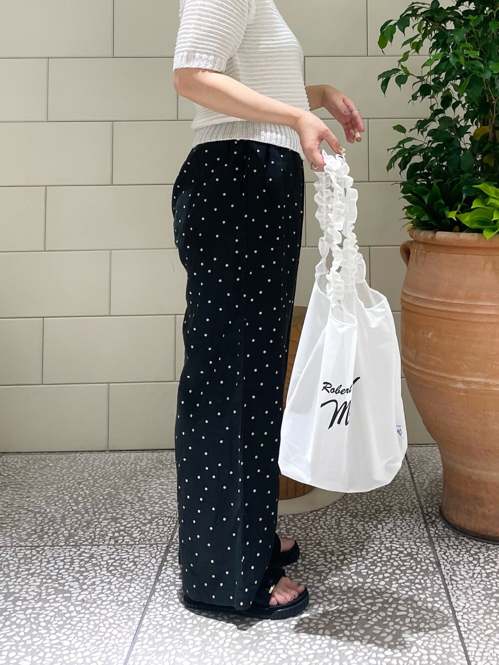 ホワイト系のニット/セーター、ブラック系のその他パンツ、ホワイト系のトートバッグを着用したレディースの春コーディネートの2枚目の写真