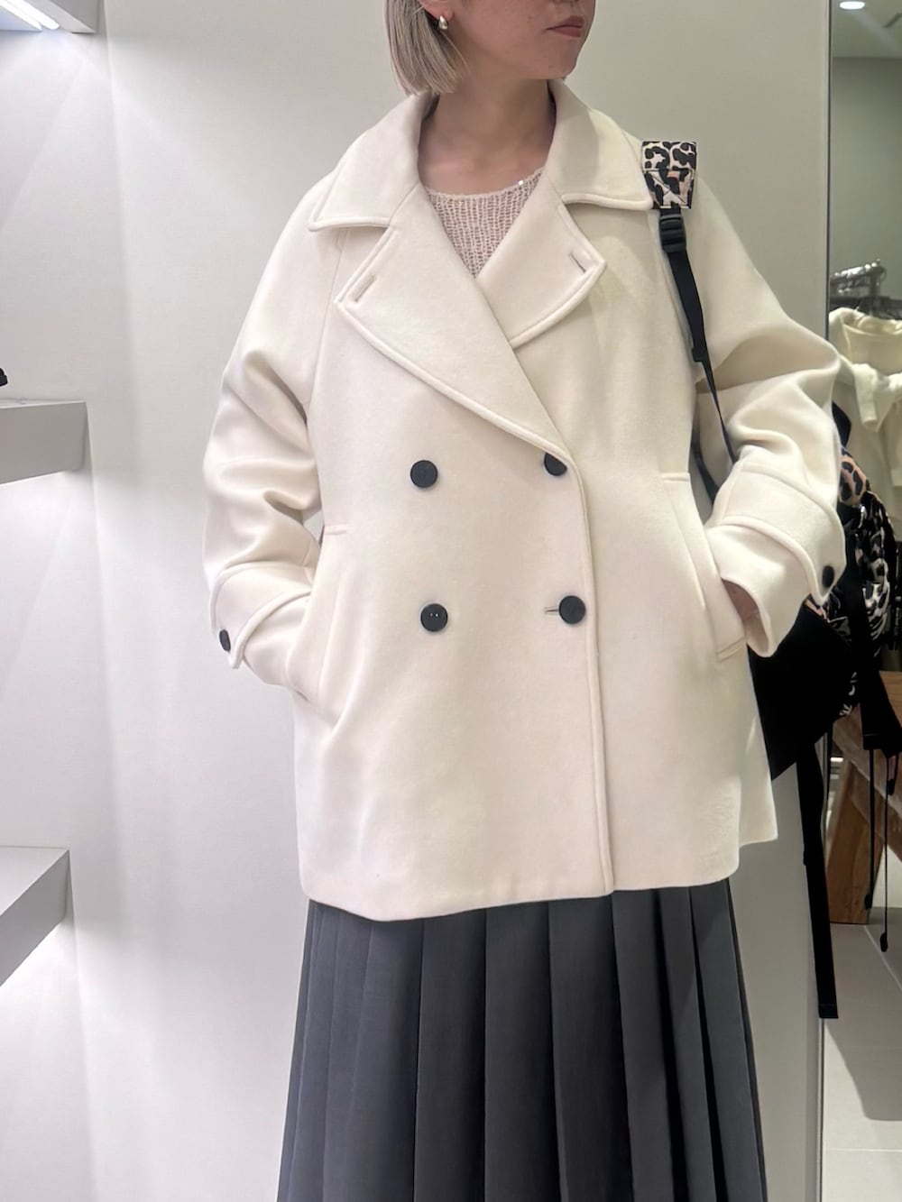 ホワイト系のピーコート、ホワイト系のニット/セーター、グリーン系のスカートを着用したレディースの冬コーディネートの3枚目の写真