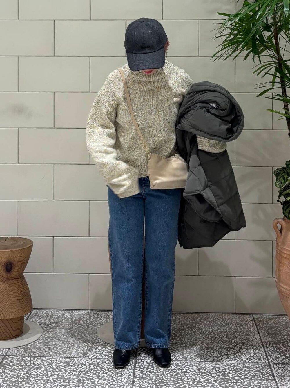 ブルー系のデニムパンツ、ベージュ系のショルダーバッグ、ホワイト系のニット/セーターを着用したレディースの冬コーディネートの2枚目の写真