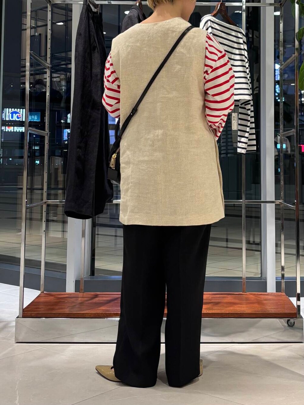 ブラック系のその他パンツ、レッド系のTシャツ/カットソー、ベージュ系のベストを着用したレディースの春コーディネートの3枚目の写真