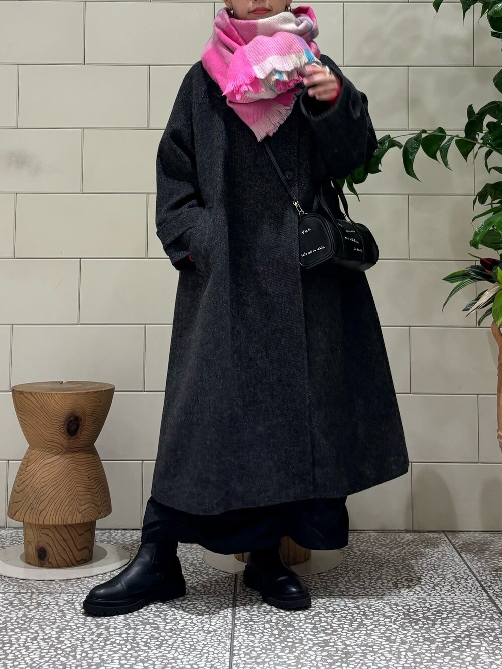 ブラック系のステンカラーコート、ブラック系のスカート、レッド系のTシャツ/カットソーを着用したレディースの秋コーディネートの2枚目の写真