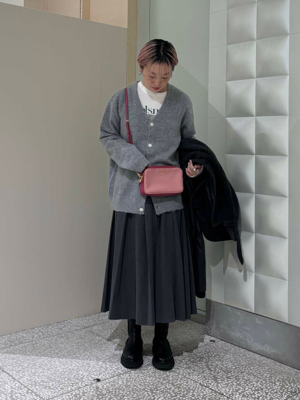 ブラック系のステンカラーコート、グレー系のスカート、グレー系のカーディガン/ボレロを着用したレディースの冬コーディネートの2枚目の写真